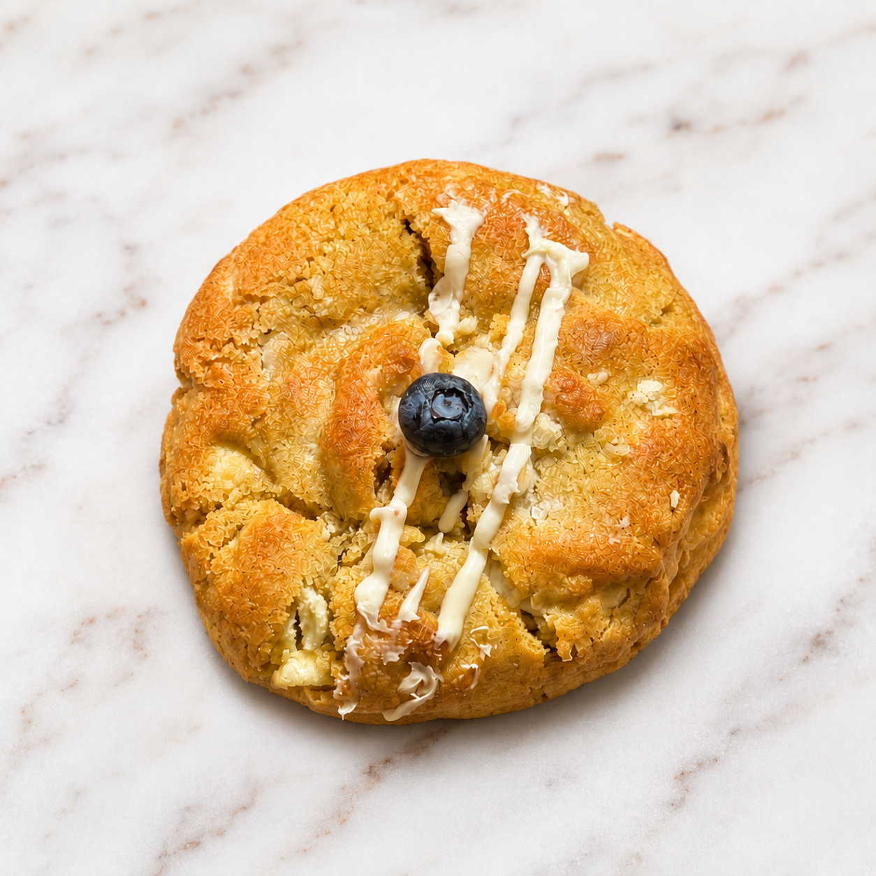 Blueberry Bliss, a golden cookie with white chocolate drizzle and a blueberry on top