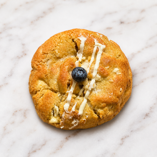 Blueberry Bliss cookie with white chocolate drizzle and a blueberry on marble